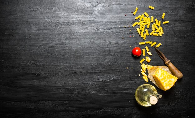 Photo pasta with cheese , olive oil and tomato on a black wooden background