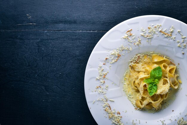 Pasta with cheese on a plate with the word paste Top view Free space for text On a wooden background