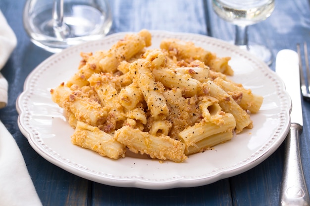 Pasta with chicken on white dish on wooden surface