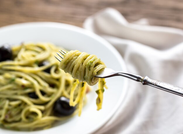 Pasta with guacamole sauce and black olives