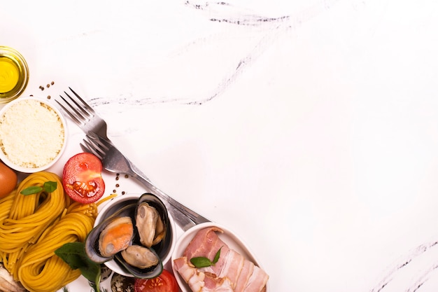 Pasta con ingredienti sul tavolo di marmo bianco