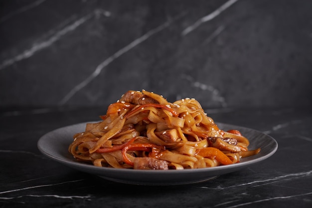 Pasta with meat, spaghetti, noodles, plate on a dark background, asian cuisine