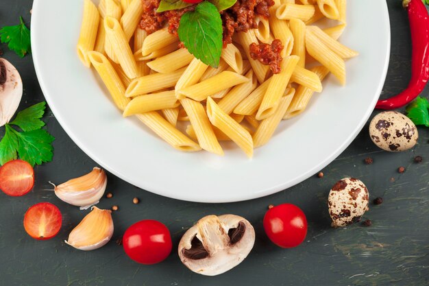 Pasta with meat, tomato sauce and vegetables on the table