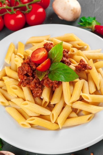 Pasta with meat, tomato sauce and vegetables on the table