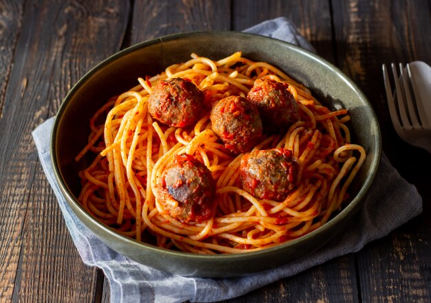 Pasta con le polpette e la salsa al pomodoro su un fondo di legno.