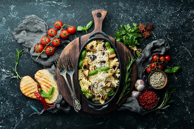 Pasta con funghi parmigiano e basilico in padella nera vista dall'alto