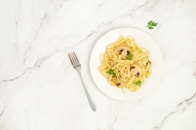 Pasta with mushrooms on white marble table