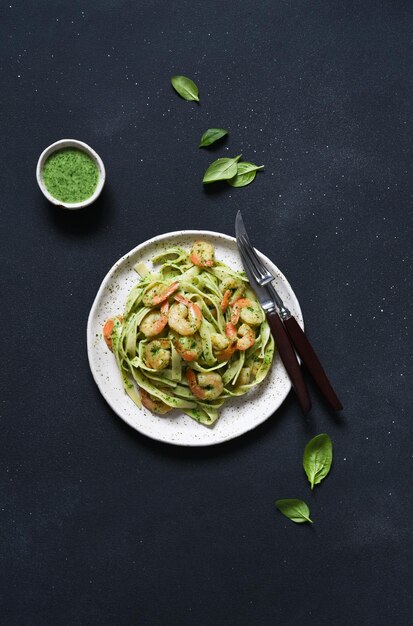 Pasta with pesto and shrimp on a plate on the kitchen table top view