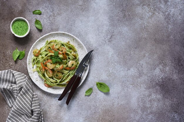 Pasta with pesto and shrimp on a plate on the kitchen table top view