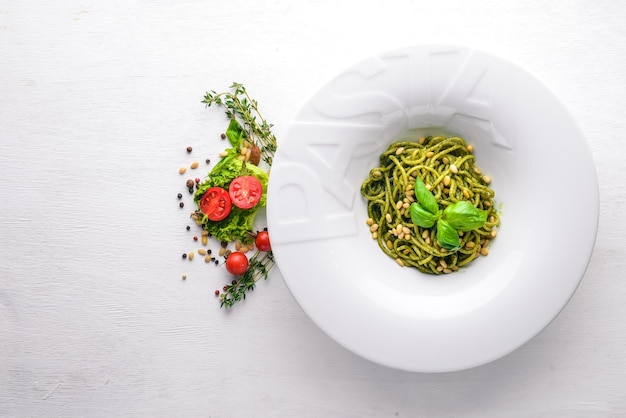 Pasta with pine nuts and greens Plate with the word paste Top view Free space for text On a wooden background