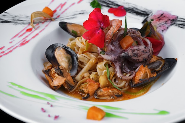 Pasta with prawns, mussels and octopus on a white plate