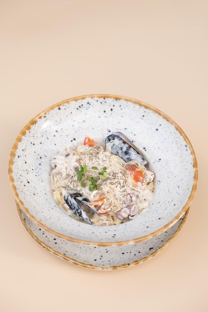 Foto pasta con frutti di mare in delicata salsa a crema vista ad angolo su sfondo beige