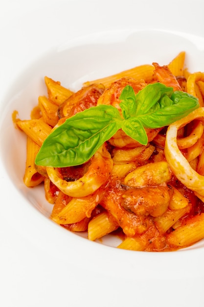 Pasta with seafood and tomato sauce close up on white