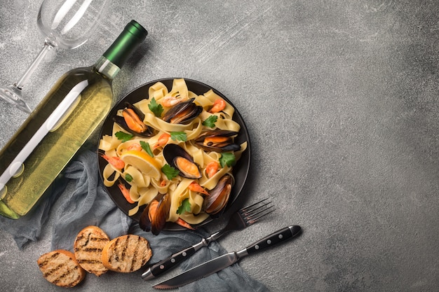 Pasta with seafood and white wine on stone table. Mussels and prawns. Top view.