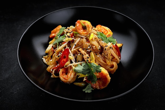 Pasta with shrimp and vegetables Asian food black plate