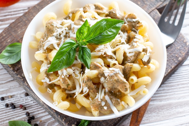 Pasta with spinach and cheese sauce on a light wooden\
background.