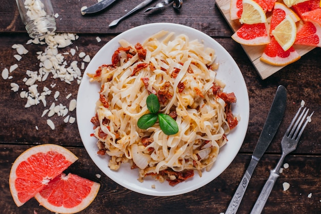 Pasta with sun-dried tomatoes on the table, restaurant dish on a wooden background top view