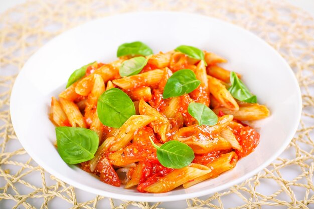 Pasta with tomato sauce and basil on table close up