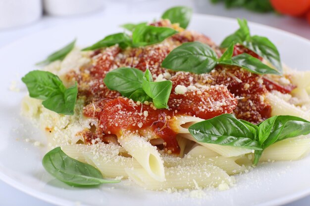 Pasta with tomato sauce and basil on table close up