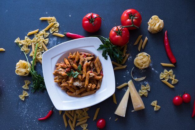 Pasta with tomato sauce, garlic, chili pepper, parmesan on white plate