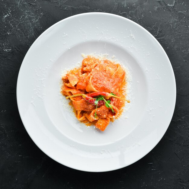 Pasta with tomatoes and chili pepper in a plate. Top view. Free space for your text.