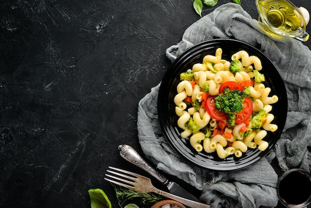 Pasta with vegetables On a black background Top view Free space for your text