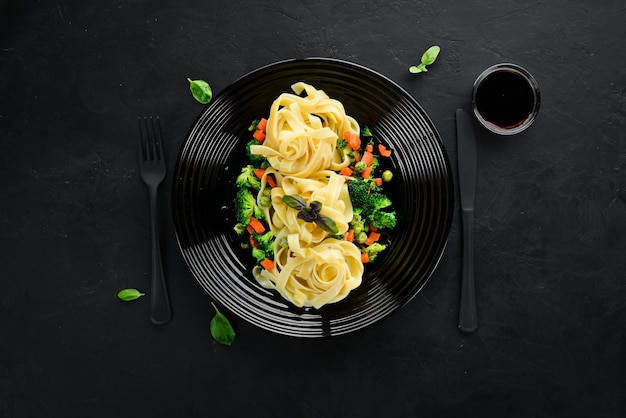 Pasta with vegetables Noodles Top view On a black background Free copy space