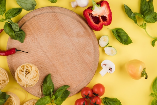 Pasta on a wooden board, vegetables, closeup. Top view. Copy space for text.