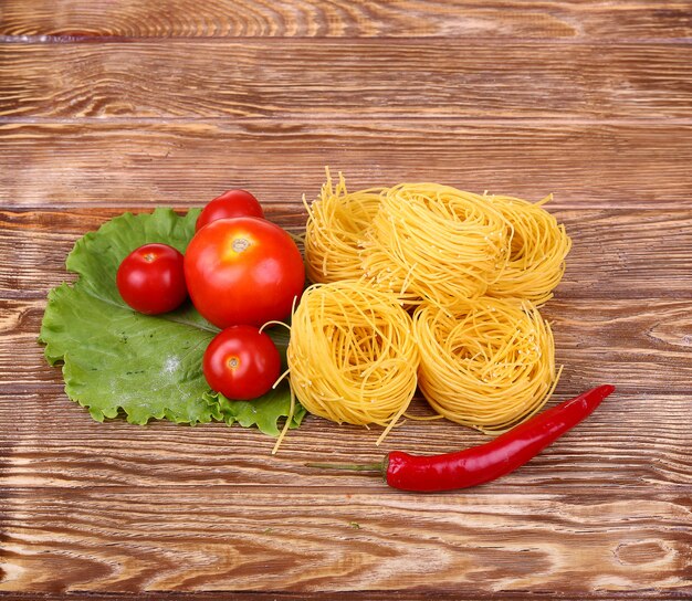 pasta on the wooden wall with tomato, lettuce pepper, and pepper