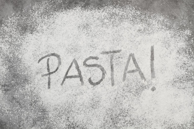 Photo pasta word write in flour on a stone background