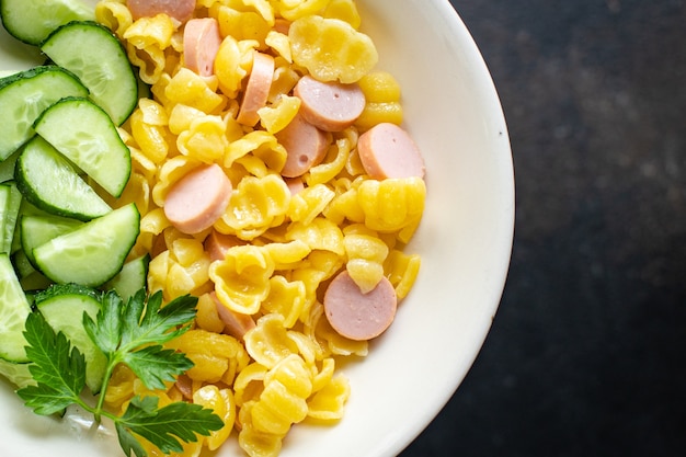 Pasta worstjes komkommer salade groenten conchiglie menu op tafel gezonde voeding