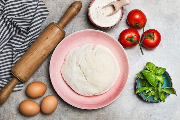 Pastadeeg op een bord en ingrediënten op een marmeren tafel