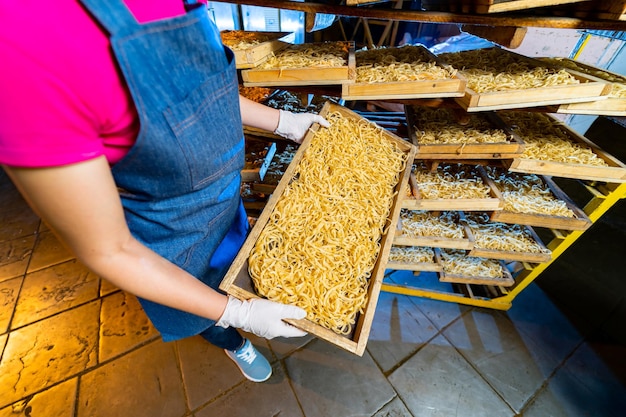 Pastafabriek Productie van pasta Krafted macaroni Werknemer met houten kist met pasta