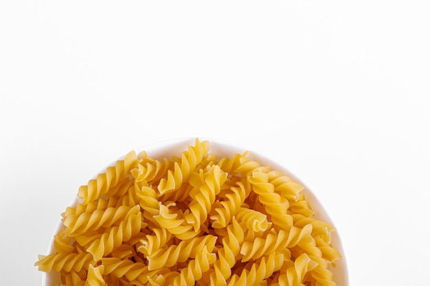 Pastaproducten in de vorm van een spiraal op een plaattextuur op een witte close-up als achtergrond