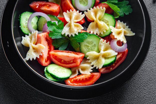 Pastasalade farfalle tomaat komkommer ui gezonde maaltijd dieet snack op tafel