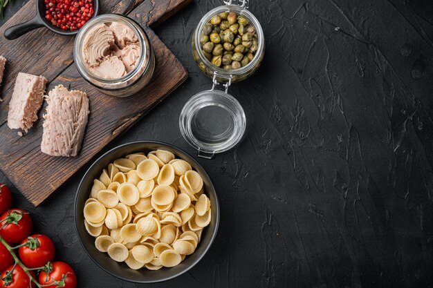 Pastasalade met tonijningrediënten op zwart, plat leggen