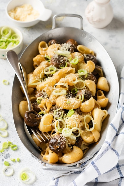 Paste Pipa Rigate and Mushrooms champignon fried in soy sauce, with pepper, parmesan cheese and steamed onions in an old metal bowl on an old vintage table