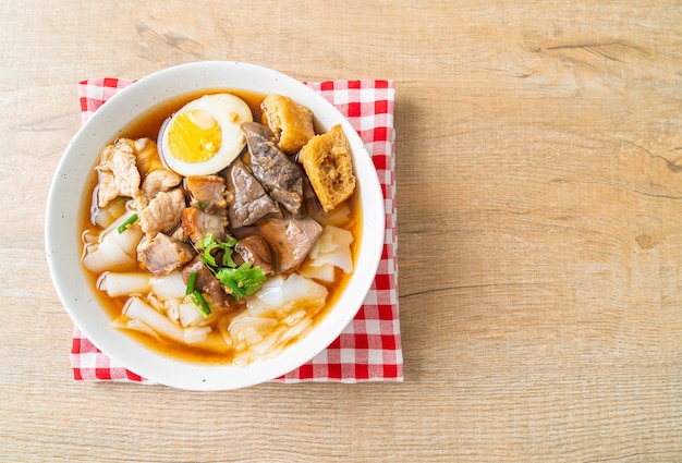 paste of rice flour or boiled Chinese pasta square with pork in brown soup - Asian food style