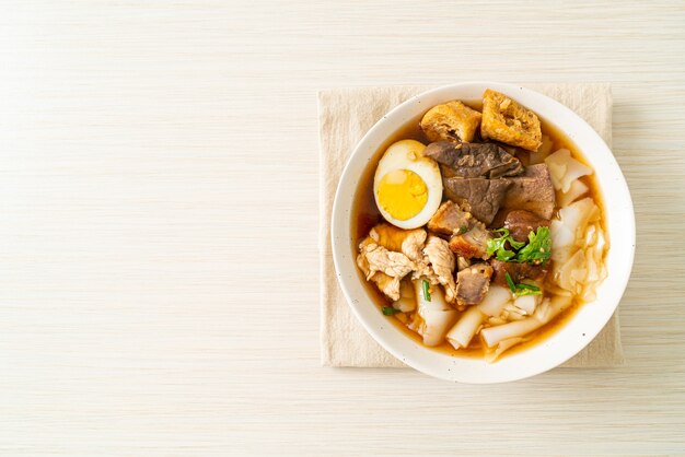 paste of rice flour or boiled Chinese pasta square with pork in brown soup - Asian food style