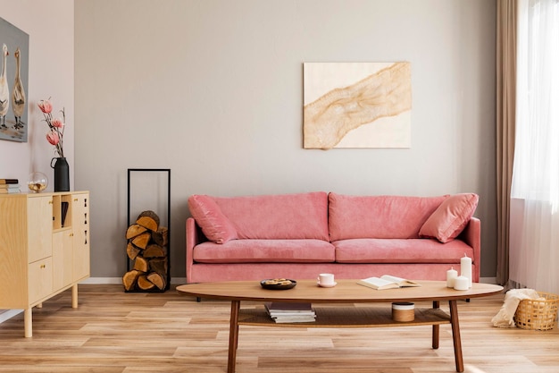 シンプルなリビング ルームのベルベット ピンクの長椅子の背後にあるベージュの壁にパステルの抽象画