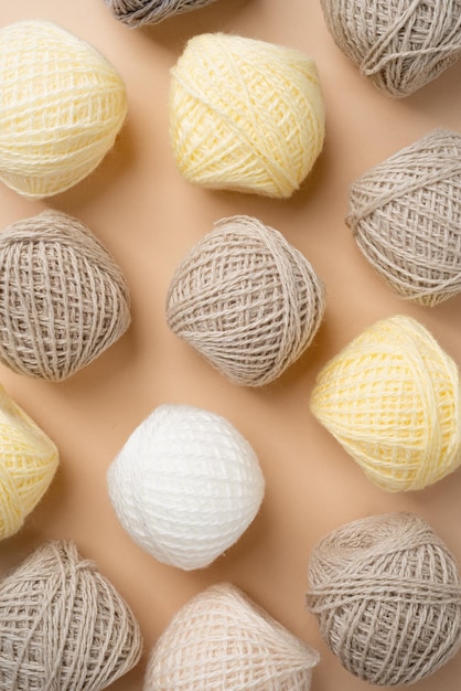 Pastel and beige colored yarn wool on beige backdrop top view\
flat lay