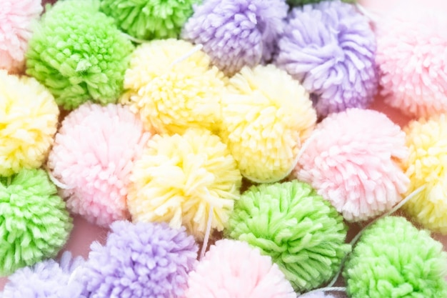 Pastel color pom poms on a pink background.