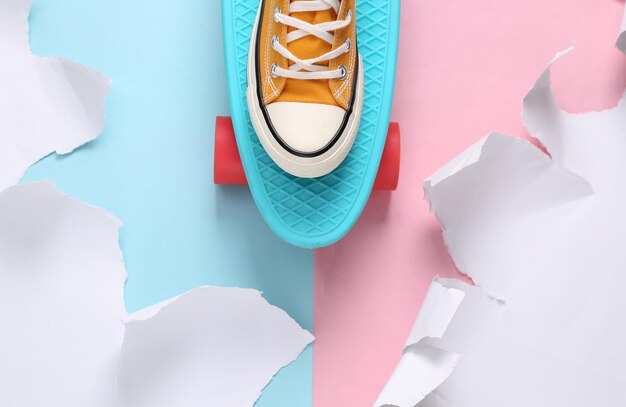 Photo pastel color trend penny board with a sneaker on a bluepink background with torn paper concept art creative layout minimalism top view