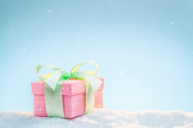 Pastel colored gift in the snow on a winter sunny day