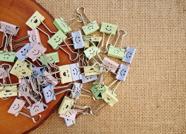 Pastel colored office paper clips smiley binder clips and pencils on notepad office supplies on a