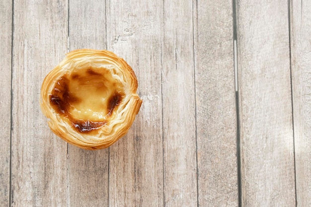 写真 ポルトガルのパステル・デ・ナタ (pastel de nata) またはパステル-デ・ベレム (pastel-de-belem) は,テキストのスペースがある木製のテーブルの上から見られる.