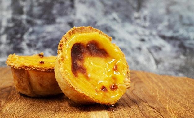 Foto pastel de nata taart of portugese ei taart op een houten bruine achtergrond pastel de belem is een kleine taart met een knapperige puff gebak korst en een custard room vulling zoet dessert