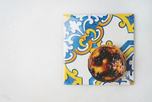 Pastel de nata. Traditional Portuguese dessert, egg tart on Traditional Azulejo tiles over marble background. Top view