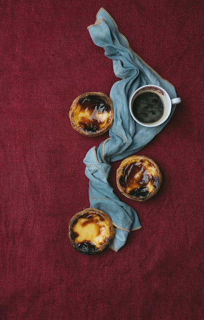 Pastel de nata. Traditioneel Portugees dessert, eitaartjes en kopje koffie op textielachtergrond versierd met servet. Bovenaanzicht