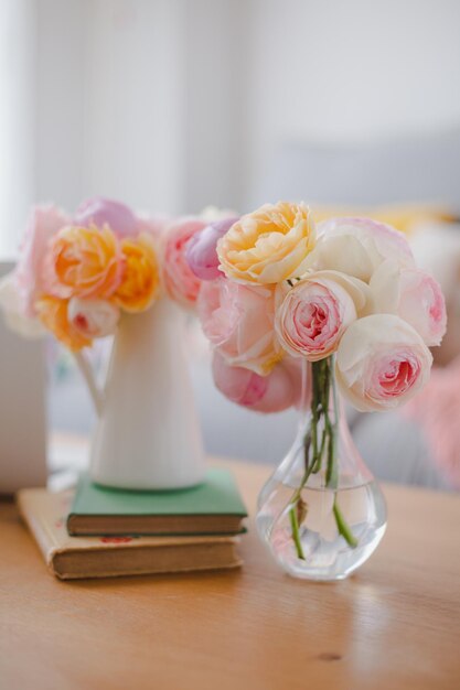 Pastel flower bouquets on wooden table with books and laptop